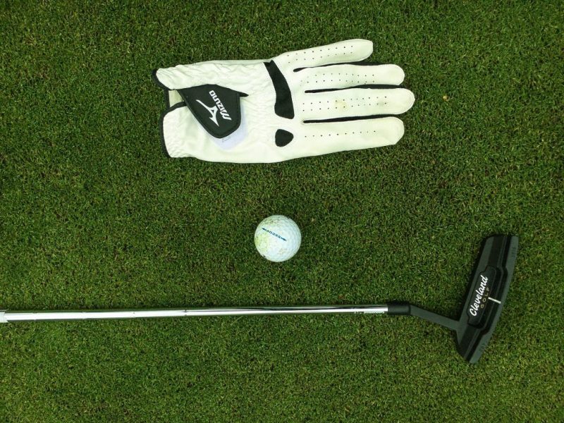 Golf Putter, Ball und Handschuh auf dem Green