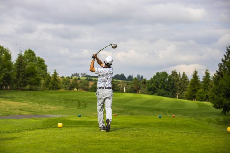 Golf Spieler schlägt Ball ab